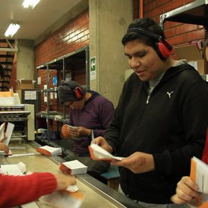 Cuatro jóvenes cierran sobres de Correos de Chile en su capacitación de Fundación Tacal.
