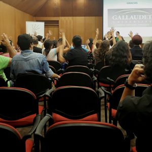 Auditorio Café Literario Parque Balmaceda donde mujeres y hombres asistentes agradecen desde sus asientos en lengua de señas al expositor del seminario.